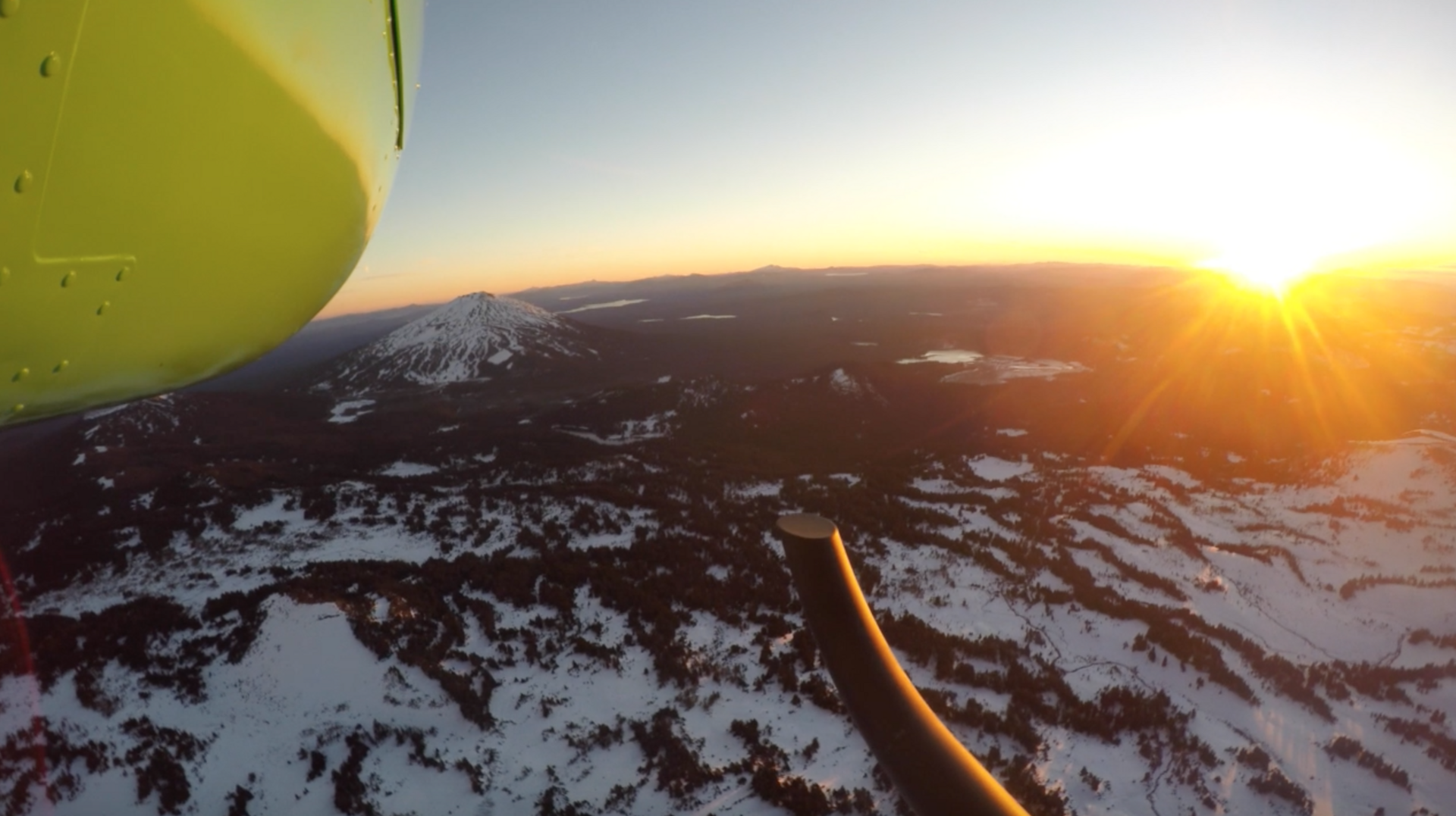 Sunset view from a helicopter above snow-covered mountains